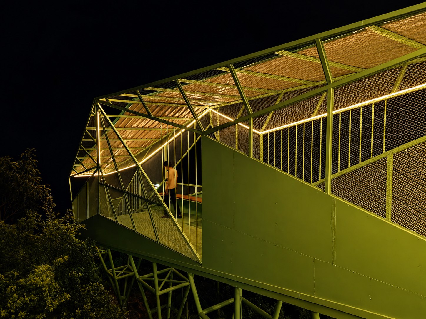 Elevated green structure with warm linear lighting at night